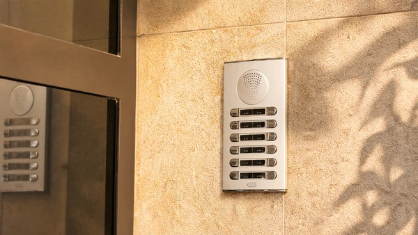 Entrée d'immeuble moderne avec interphone vidéo numérique installé sur mur texturé sombre